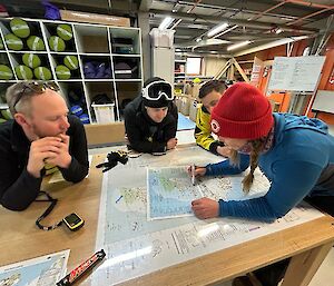 Four expeditioners around a table planning their route on a map