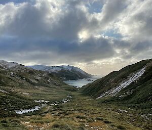 The same grassy slope as previously with snow on the hill tops