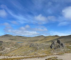 Blue skies and grassy hills with jagged rocks sticking out