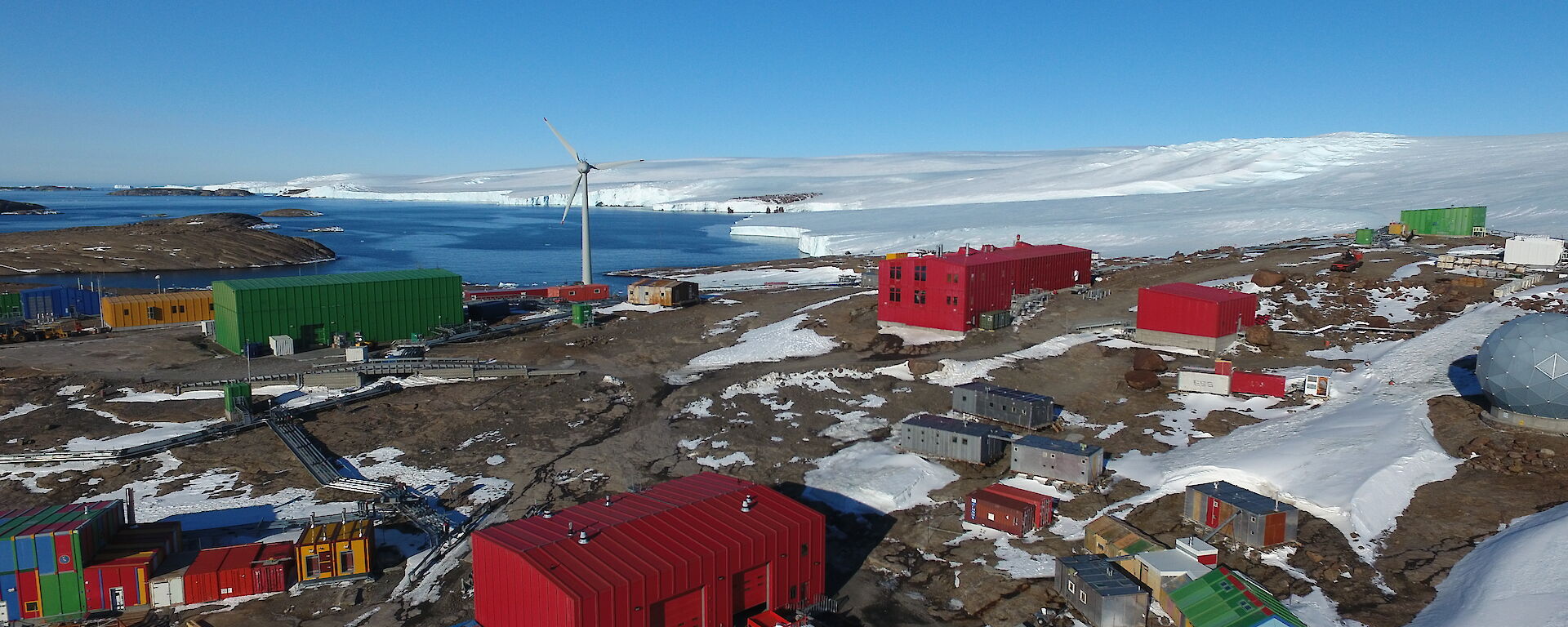 A cluster of brightly coloured buildings with the sea in the background and snow covered hills