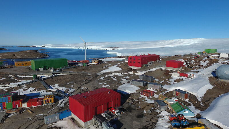 A cluster of brightly coloured buildings with the sea in the background and snow covered hills