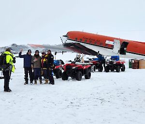 A group of people stand in front of quad bikes and a Basler aircraft