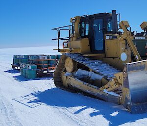 Bulldozer towing two sleds of ATK in 44 gallon drums