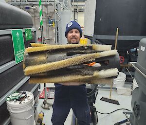 plumber holding up a large pipe brush that breaks down sewer solids