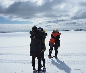 two pairs of runners hug on completion of the marathon effort