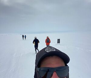 Selfie of a smiling runner with fellow runners in the background