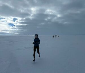 smiling marathon runner on snow track with other runners in teh background