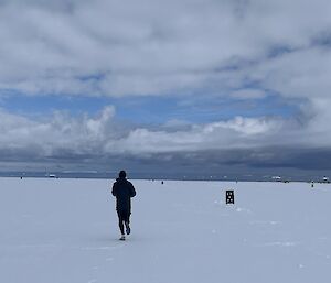 runner on snow track with icebergs in the distance