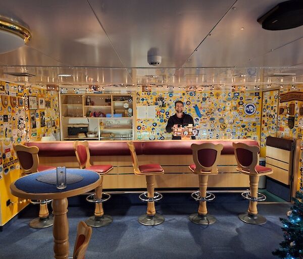 A bar with bar stools and memorabilia on the while behind