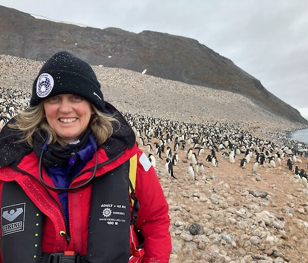 A woman in red Antarctic gear and an AAP beanie smiling into the camera