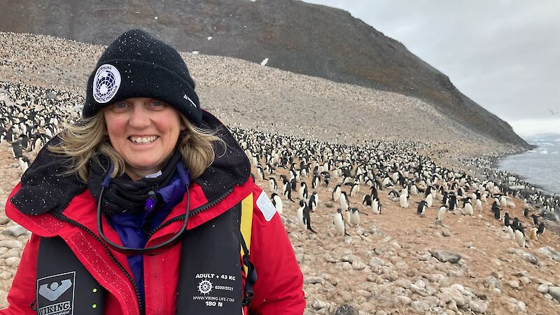 A woman in red Antarctic gear and an AAP beanie smiling into the camera