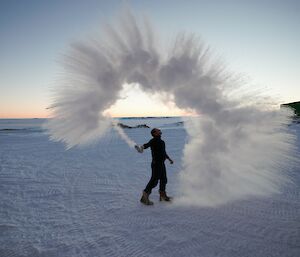 A man surrounded by an arc of jagged steam at sunrise.