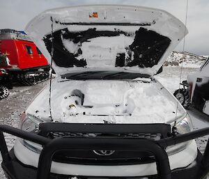 A car with its bonnet up, filled with snow.