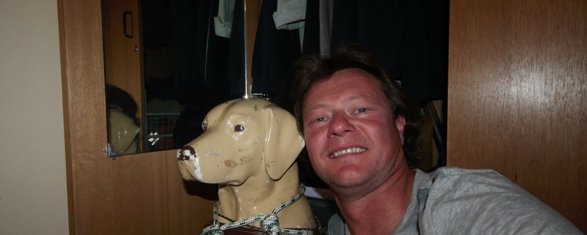 A man posing with a plastic guide dog figure.