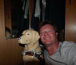 A man posing with a plastic guide dog figure.