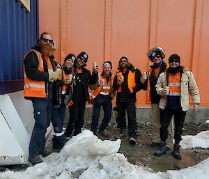 Seven Casey station electricians pose for a photo in outside workshop with some beverages