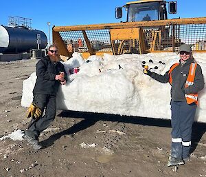 two electricians holding some beverages up at the trade BBQ in front of a big snow esky