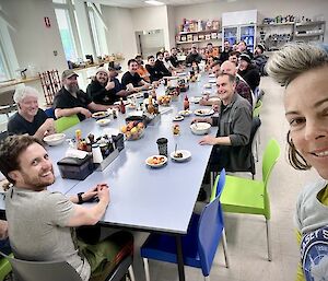 a group of smiling people sit around a large table. all smiles.