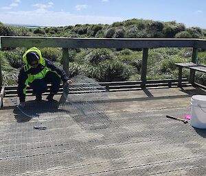 A person places wire on a timber viewing platform