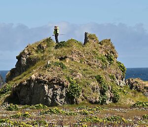 A person stands on a large rocky mound