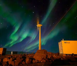 A brilliant green aurora australis with the wind turbine in the foreground.