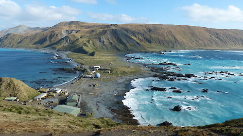 High up view of Macquarie Island station with narrow isthmus in the foreground and high hills at the back