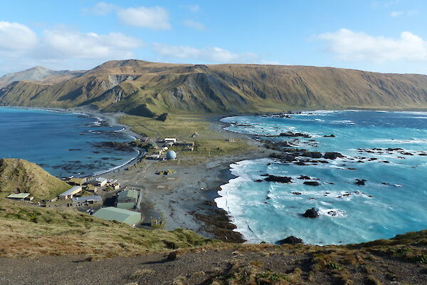 High up view of Macquarie Island station with narrow isthmus in the foreground and high hills at the back