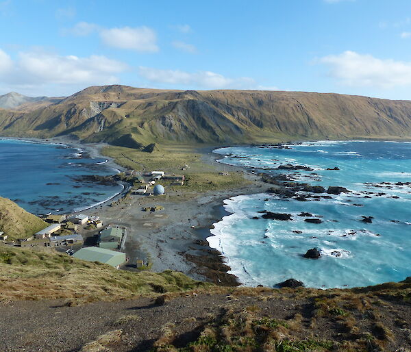 High up view of Macquarie Island station with narrow isthmus in the foreground and high hills at the back