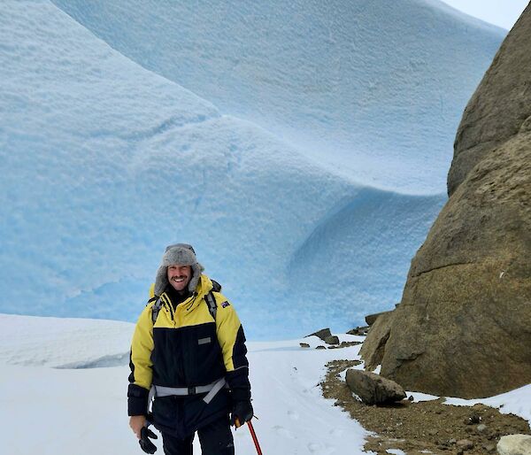 An expeditioner dressed in winter field gear on the ice near rocky Mt Henderson in the station operational area around Mawson Station