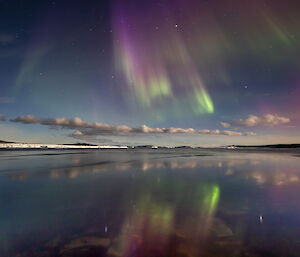 Colourful auroral lights are almost perfectly mirrored in thre harbour waters in front of Mawson station recently