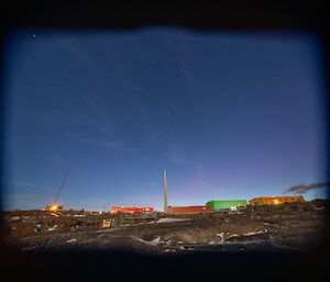 Faint aurora can be seen in the night sky with the station buildings in the foreground
