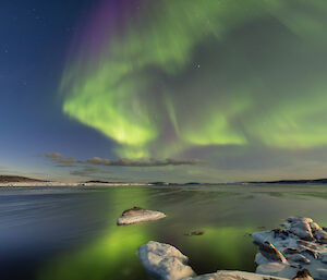 An aurora of green curtains of light fringed with purple above Horseshoe Harbour near Mawson station