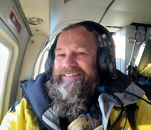 A bearded man smiling sitting in a helicopter