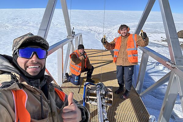 Three expeditioners, all plumbers, working on the bridge over the melt bell, used to extract fresh potable water for Mawson Research Station in East Antarctica