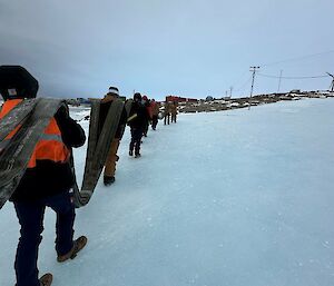 Expeditioners at Mawson heading over a patch of blue ice on the trip back to the station with a section of refuelling hose recently