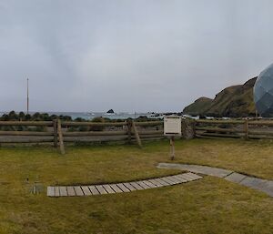 A panoramic view of huts and weather instruments installed on flat, vegetated ground at Macquarie Island.