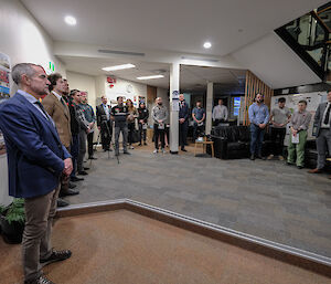 A group of people standing with solemnity in a room,