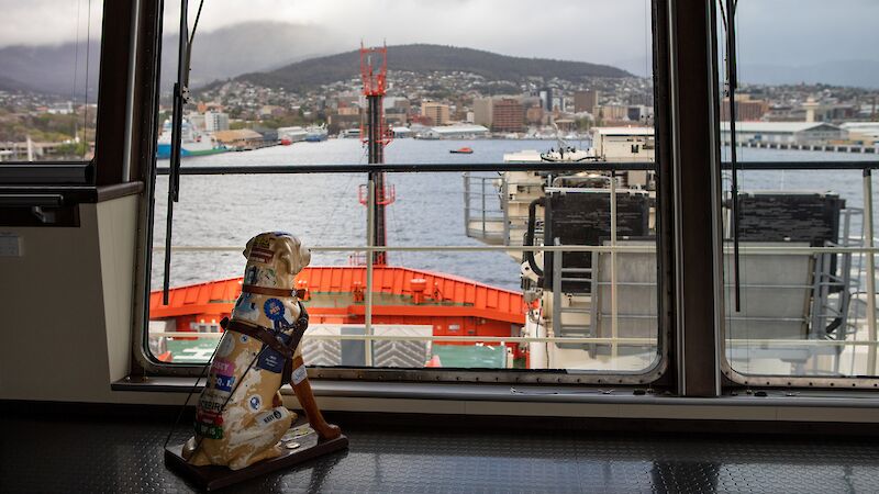 A fibreglass collection dog sits on the bridge of Nuyina, looking out to the river.