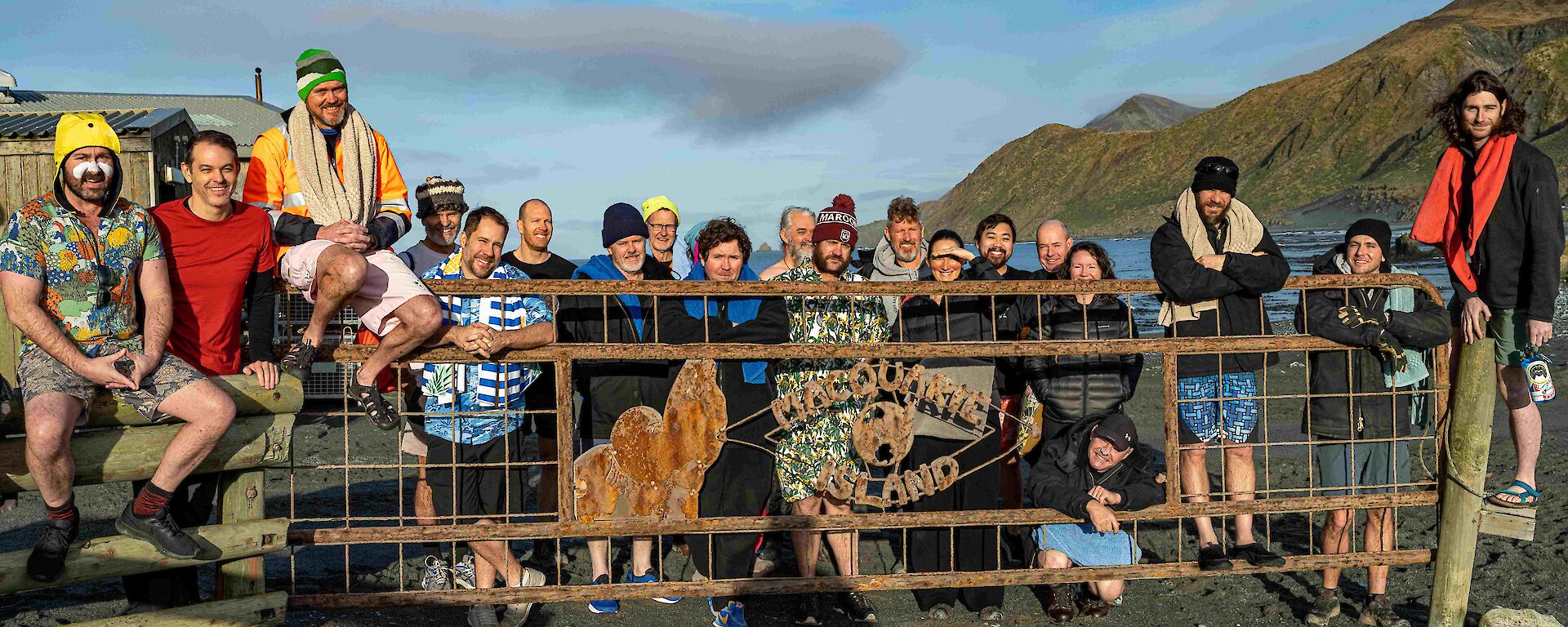 People stand behind a gate with hills and blue sky behidn them.