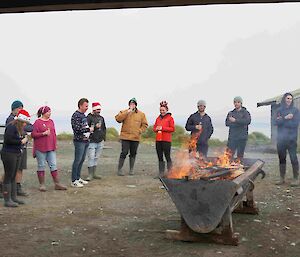 A group of people stand around a fire in a drum