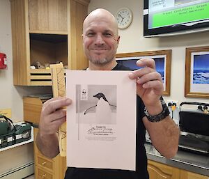 Chef Justin Chambers holding a certificate of penguin adoption  through the WWF