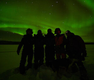 5 people silhouette foreground to a vibrant Aurora Borealis