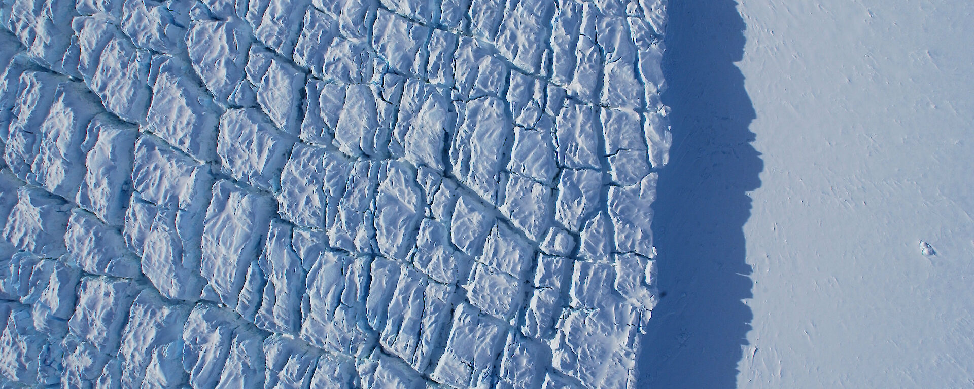 An aerial view of sea ice covered in rectangular-shaped cracks