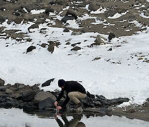 An expeditioner taking a sample from Deep Lake