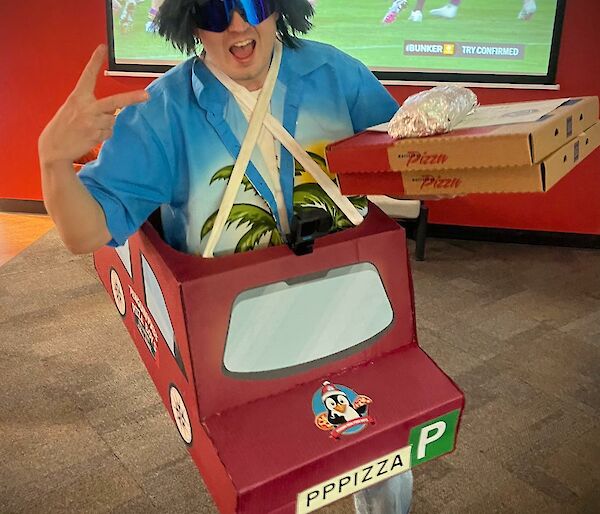 Expeditioner Dan in a custom cupboard cut out delivery car delivering pizzas to Splinters Bar.