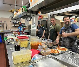 Four casey members in the kitchen with a pizza production line, big smiles!