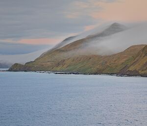 Mist-covered peaks on the hillside of an island, sea in the foreground