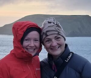 A woman in red parka smiling, with a smiling woman in a beanie.