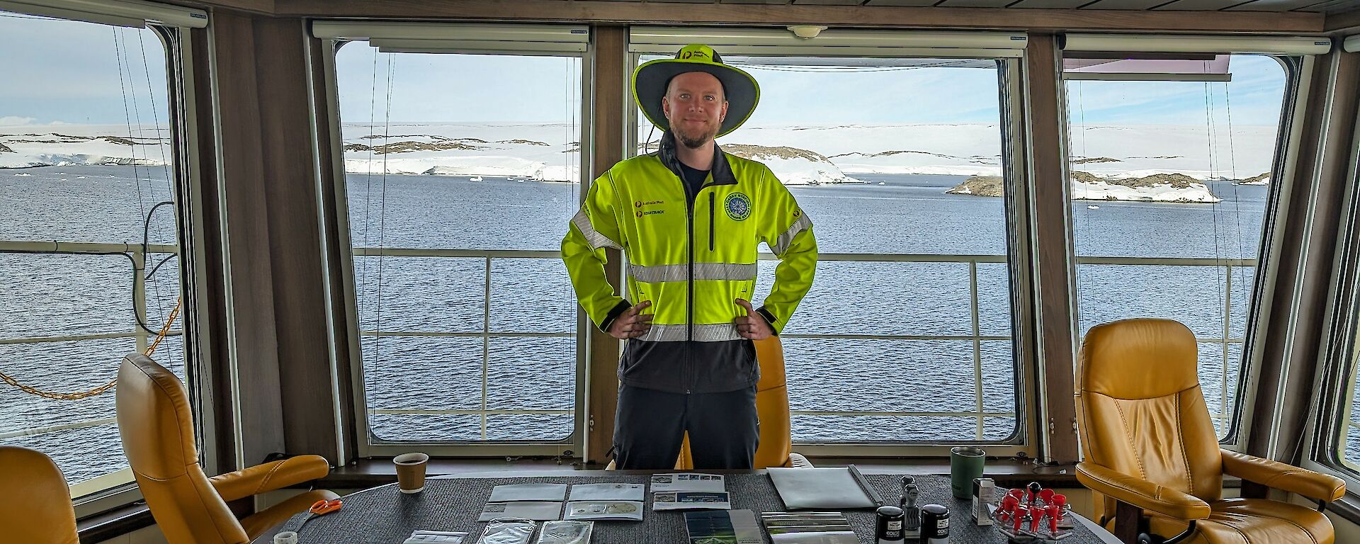 Expeditioner postmaster Owen stands behind table with post supplies aboard RSV Nuyina