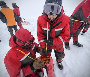 team member mitch and kim packing away a 100 metre-long rope on the sea ice